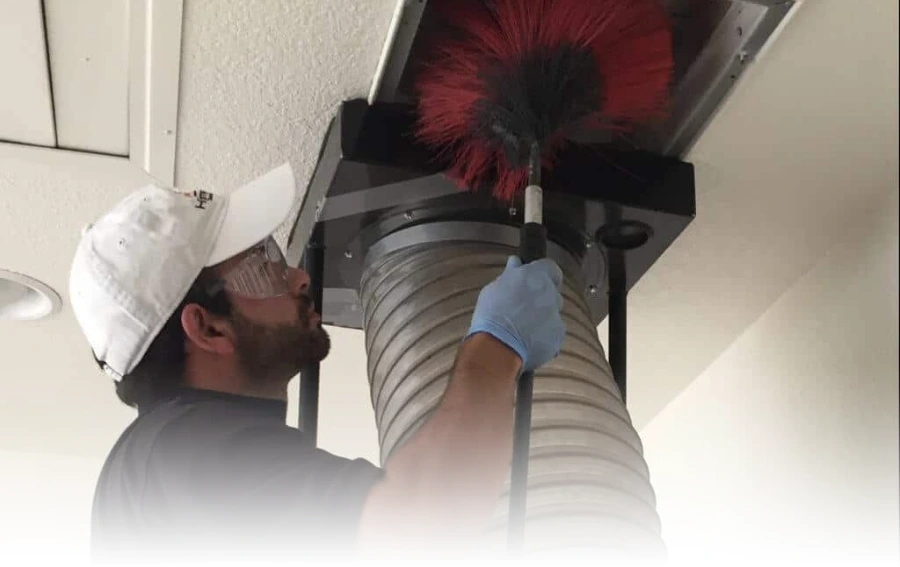 Professional Using Vacuum Hose for Duct Cleaning – "Air duct technician using a high-powered vacuum hose to remove dust and debris from a ceiling duct system in NJ."