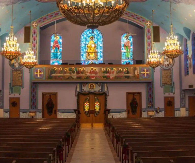 Interior of St. Nicholas Ukrainian Catholic Church in Passaic, NJ, showcasing ornate chandeliers, vibrant stained glass, and traditional Eastern European decor.